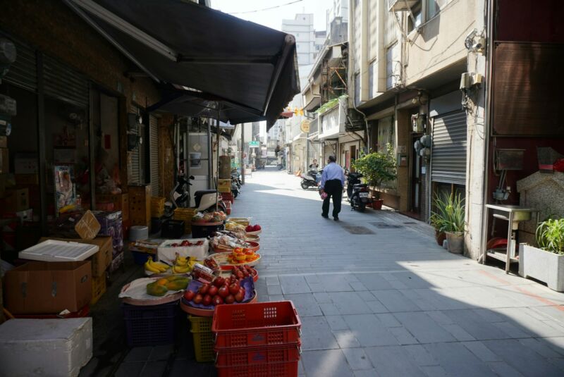 A man walking down a street next to a building