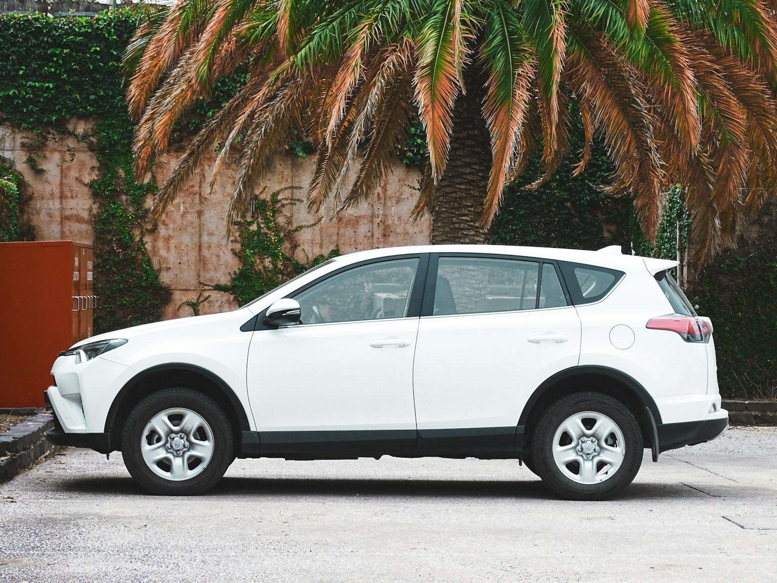 Photo by Vlad Kutepov white suv parked near palm tree during daytime