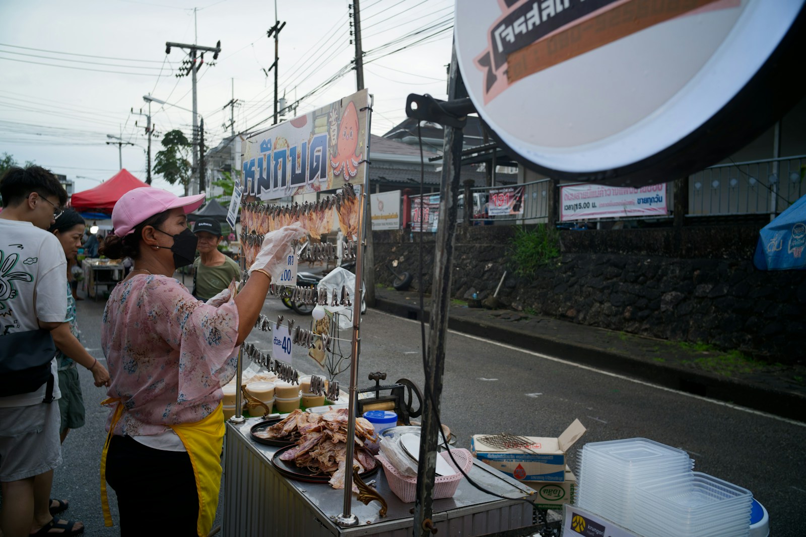 Vendor serves food at an outdoor market stall.