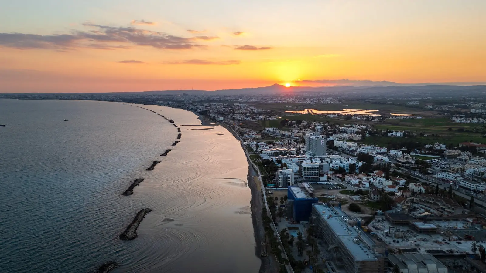 Aerial view of Limassol's coastline during sunset, showcasing the vibrant city and serene sea.