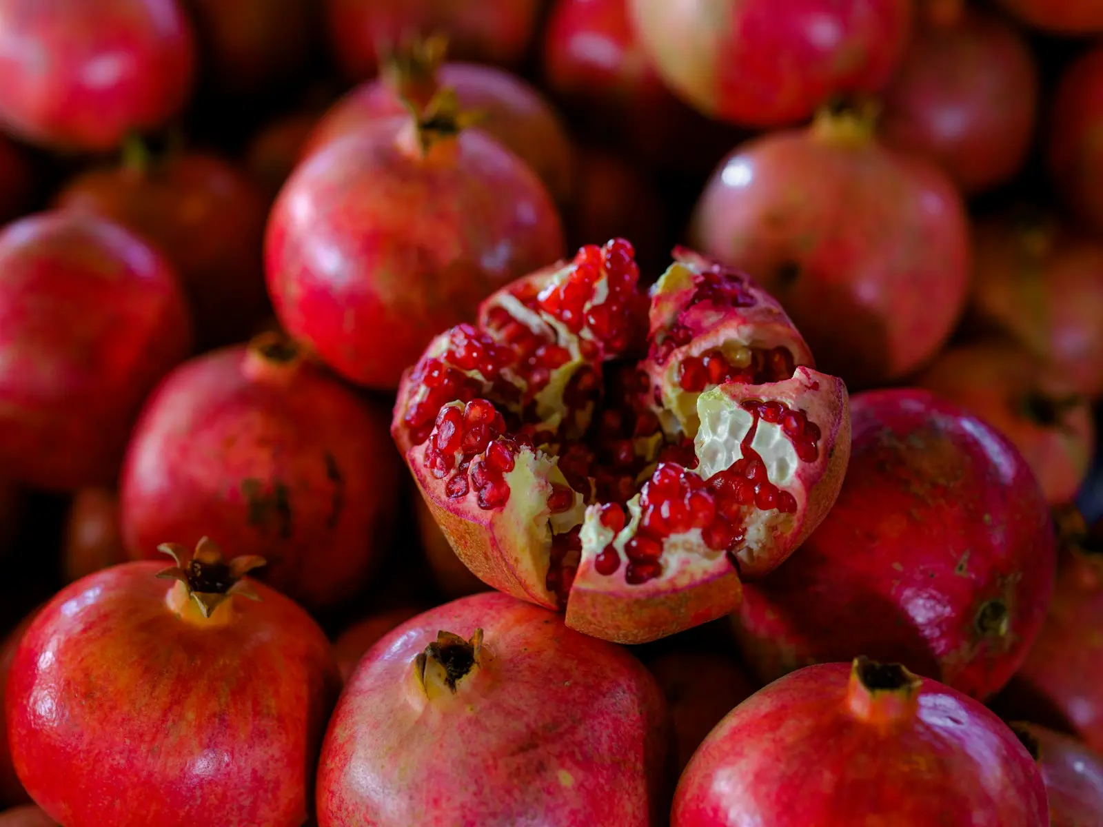 a pile of pomegranates with one cut in half