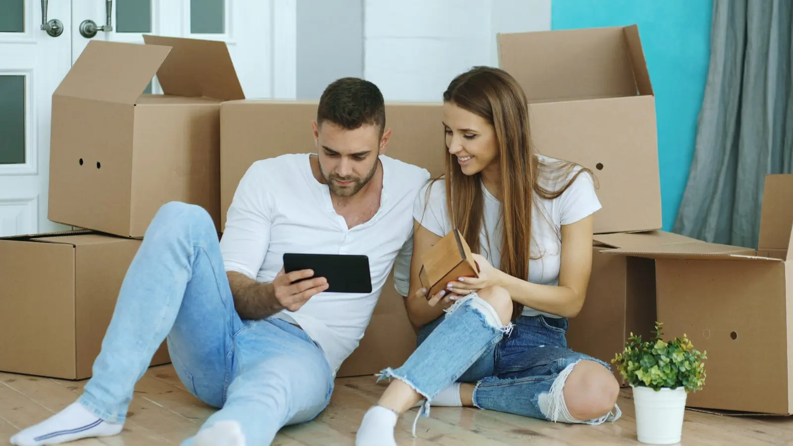 Couple looking at tablet surrounded by moving boxes