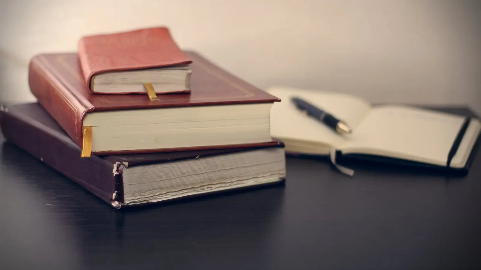 Photo by Mikhail Pavstyuk selective focus photography of three books beside opened notebook