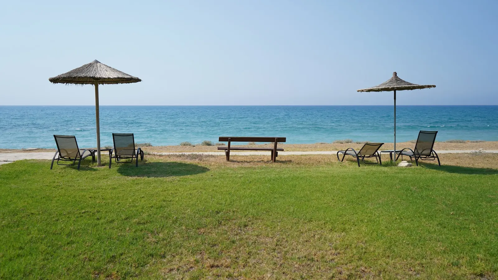 Photo by GEORGE LIVADHIOTIS a couple of lawn chairs sitting on top of a lush green field